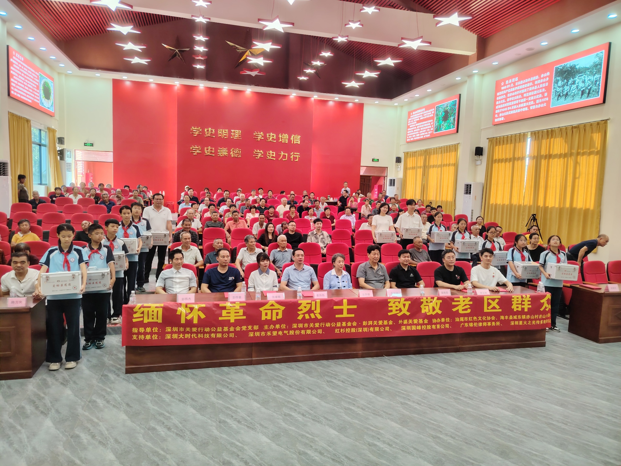 慰问捐赠现场 · 各界爱心代表在赤山人民礼堂舞台交接福寿敬老包、爱幼医药箱等慰问物资